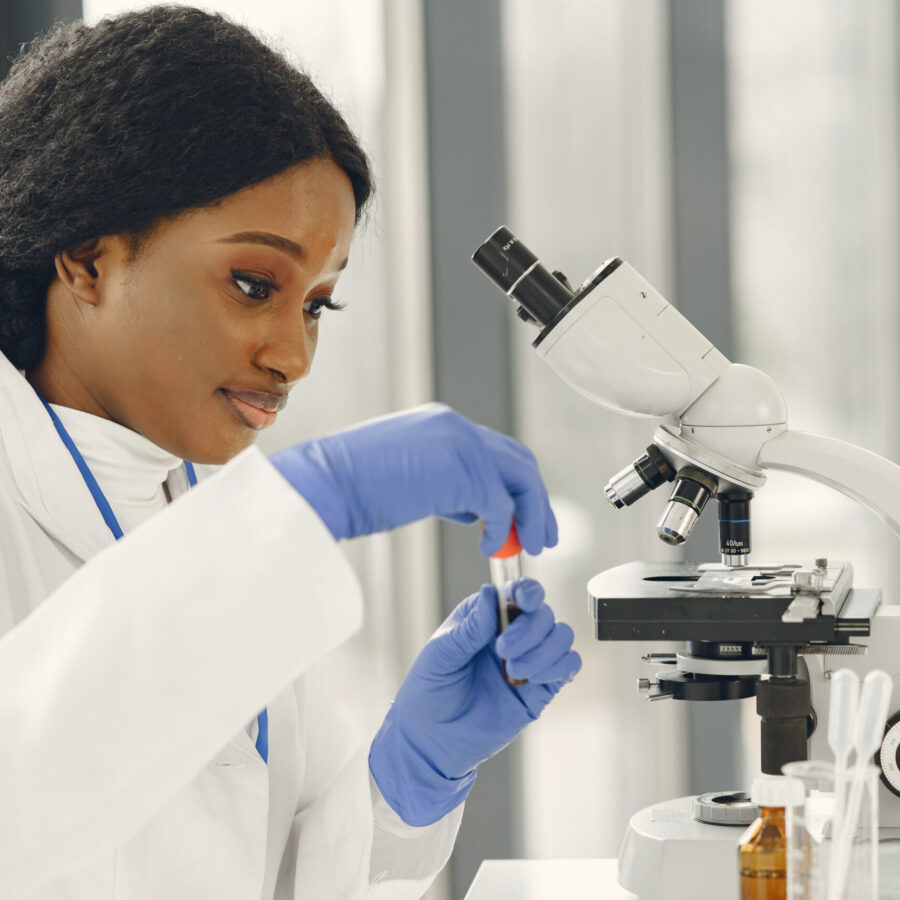 Medical doctor girl working with a microscope. Young female scientist doing vaccine research.
